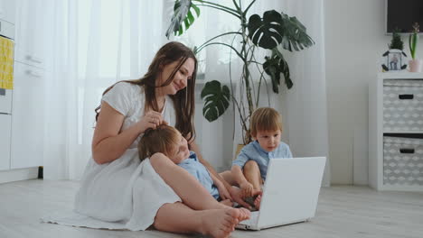 Schöne-Moderne-Junge-Familie,-Die-Zu-Hause-Auf-Dem-Boden-Liegt-Und-Etwas-Am-Laptop-Macht